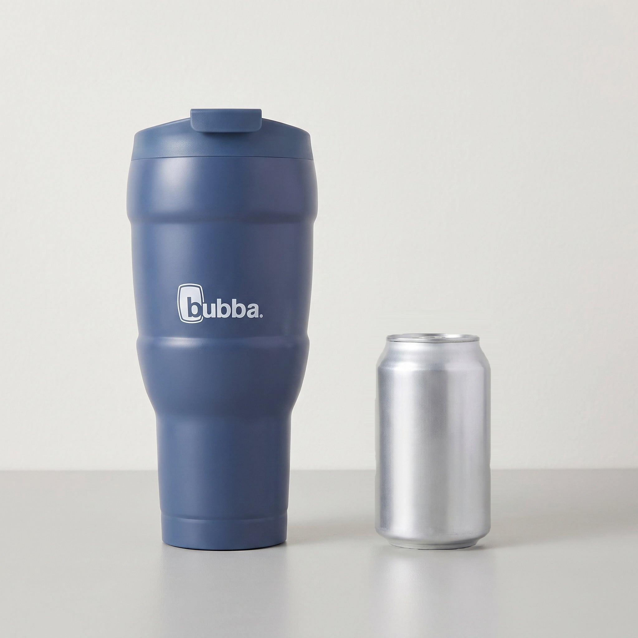 bubba 24 oz Hero XL Tumbler in Indigo standing beside a 355 ml can for size comparison. It stands 10.0 in tall.