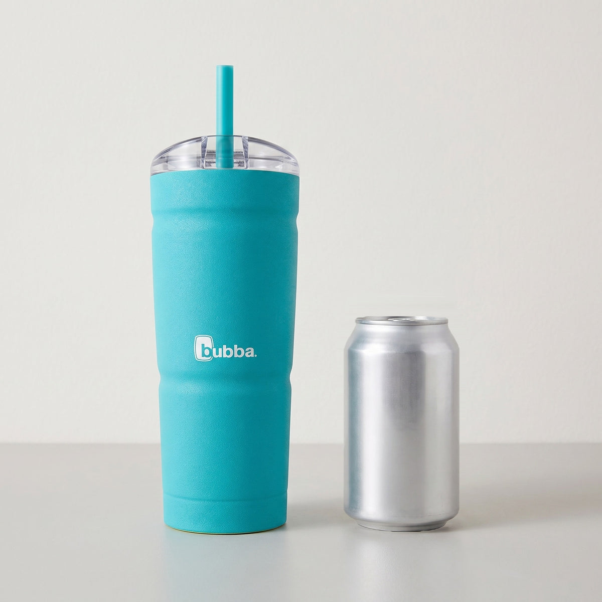 bubba 24 oz Envy S Tumbler in Scuba standing beside a 355 ml can for size comparison. It stands 9 in tall (10.5 in with the straw up).
