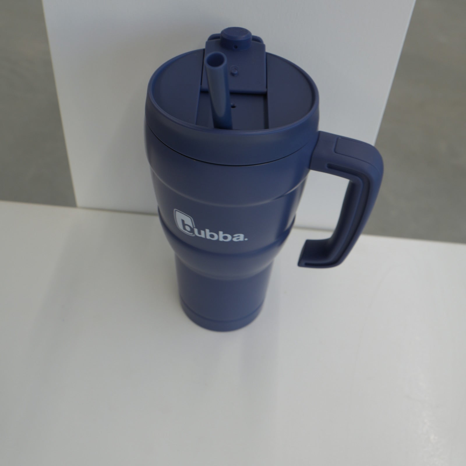 bubba 24 oz Hero XL tumbler in Indigo on its side, showing the straw lid and carry handle